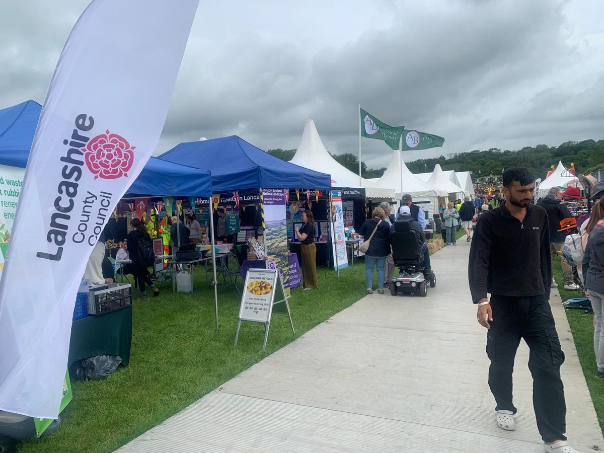 Stalls and visitors at the Royal Lancashire Agricultural Show, with a Lancashire County Council banner in the foreground